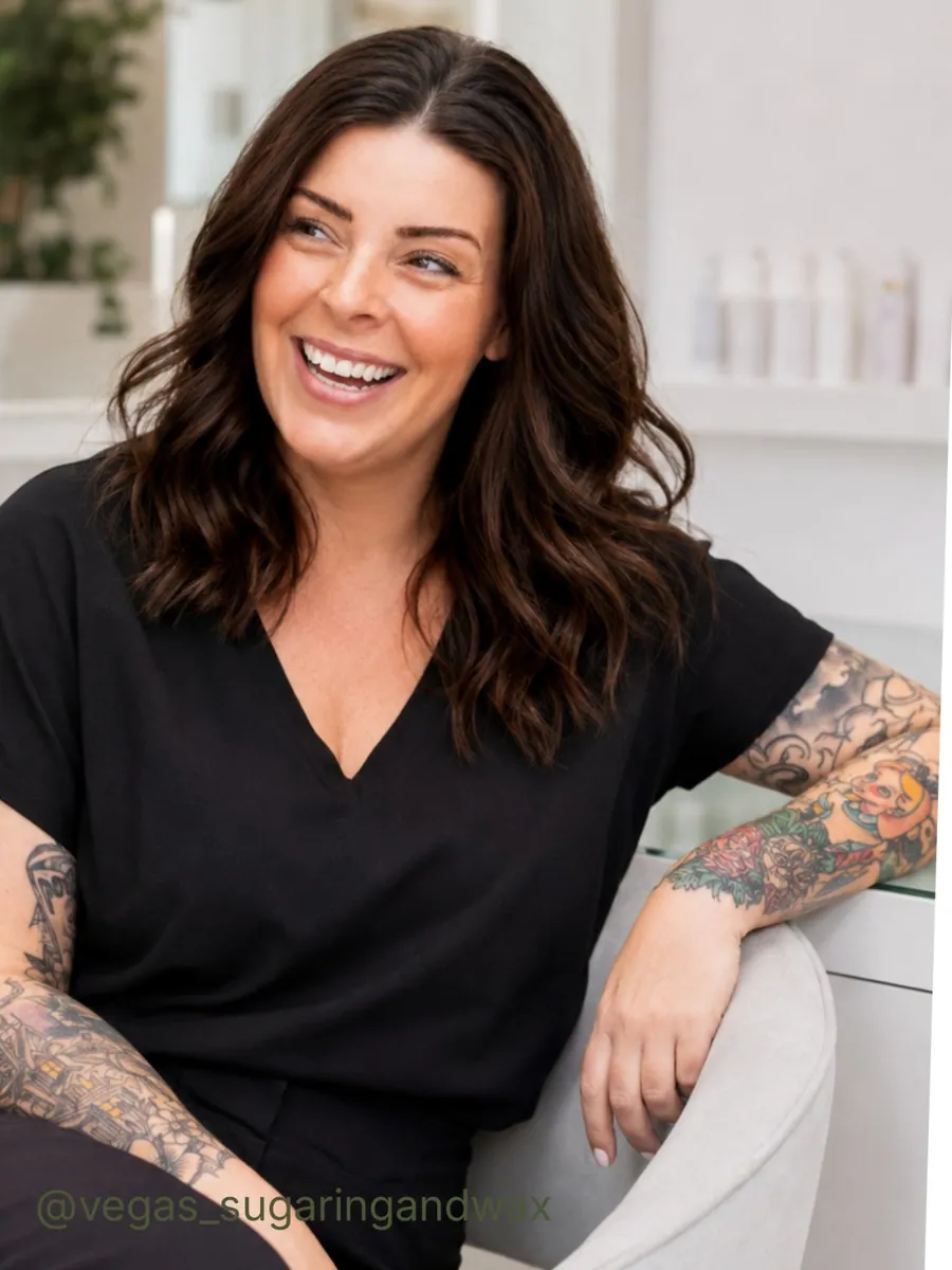 Vegas Sugaring & Wax owner smiling in her studio, wearing black with her tattoos visible